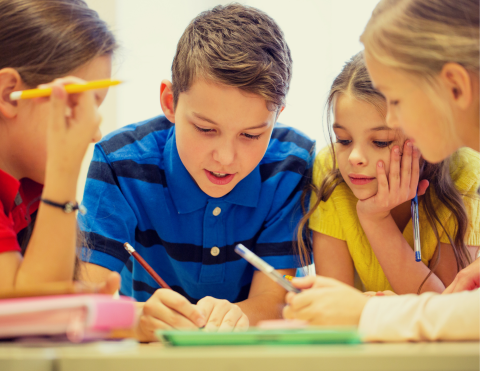 Four children concentrating on writing something.