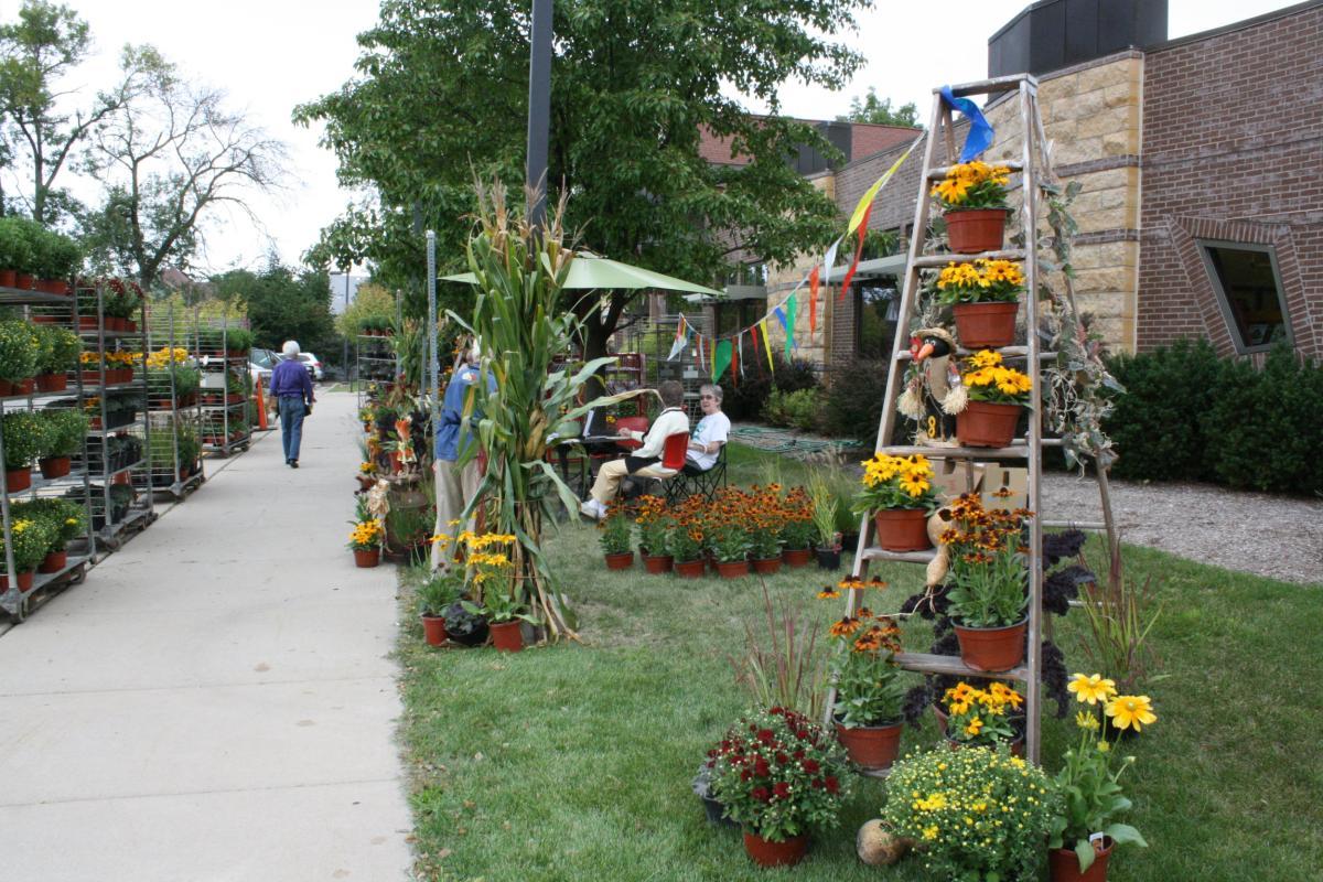 Photograph of a plant sale outside the front of the Woodstock Public Library.